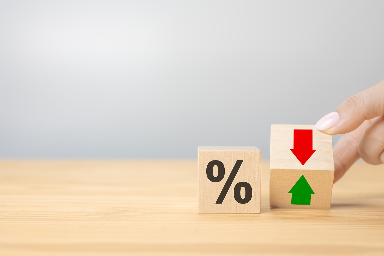 Hand flip wood cube change arrow down to up. Changes in interest rates. Hand is turning a dice and changes the direction of an arrow symbolizing that the interest rates are going down